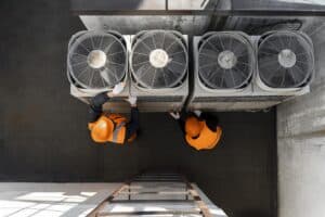 Two men seen working on HVAC equipment from above