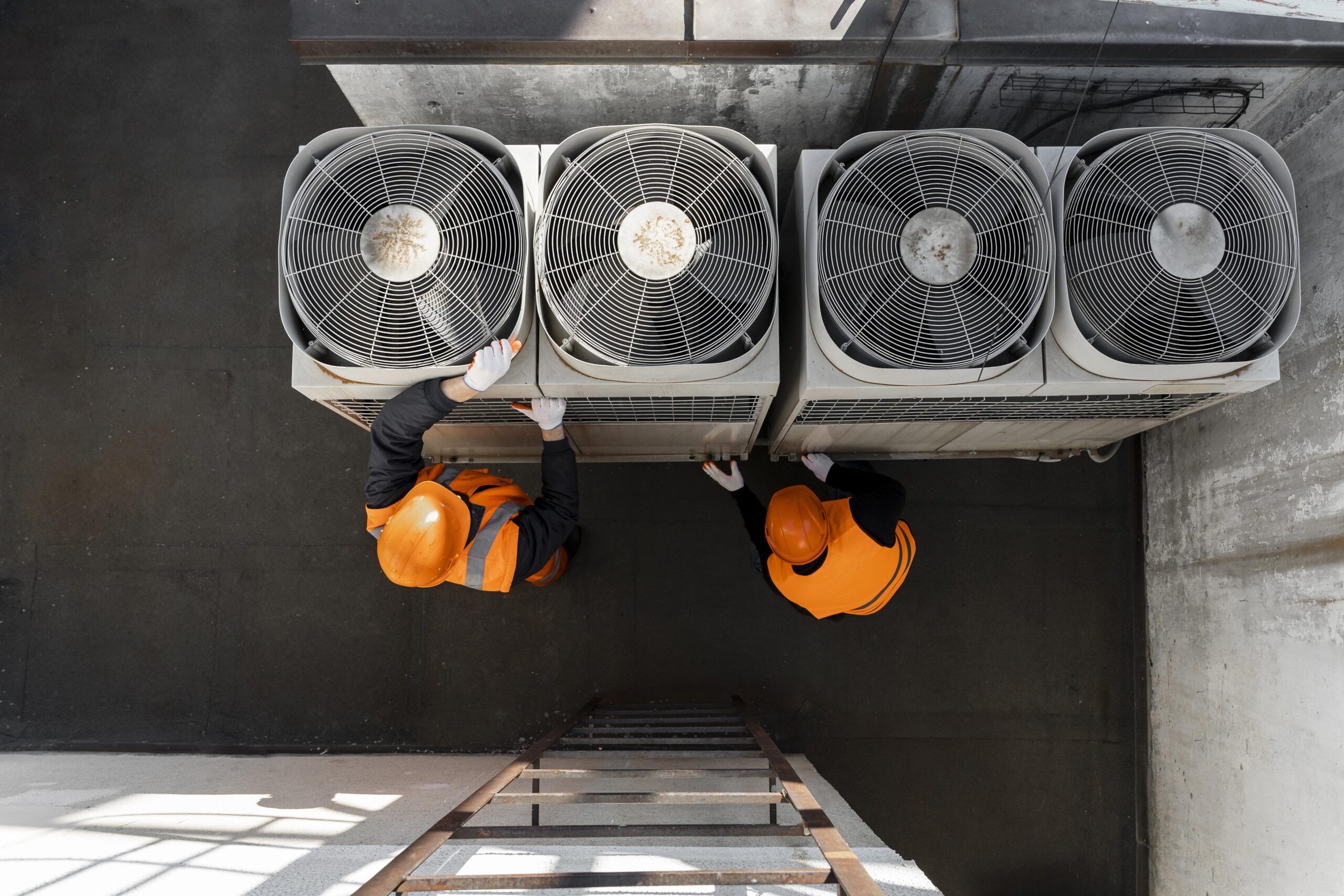Two men seen working on HVAC equipment from above