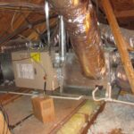 A view of a furnace and ductwork installed in an attic, showcasing essential components of a home's heating system.