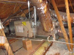 A view of a furnace and ductwork installed in an attic, showcasing essential components of a home's heating system.