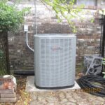A heat pump located in front of a brick wall, illustrating the integration of efficient heating solutions with architectural elements.