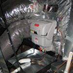 An attic featuring a complex duct system with various pipes and ducts arranged throughout the space.