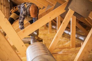 An HVAC technician works on an air duct
