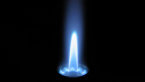 A blue flame burns brightly against a dark background