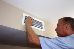 Man adjusting HVAC damper on wall
