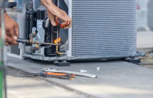 Technician performing emergency HVAC repair on outdoor unit for Total Air